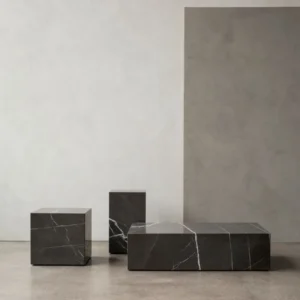 Three dark marble cubes of varying sizes on a concrete floor.