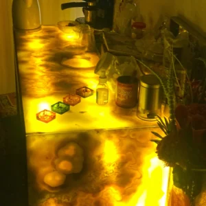 Illuminated onyx countertop with candles, flowers, and apothecary items.