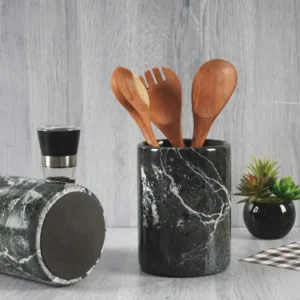 Black marble utensil holder with wooden spoons and a pepper grinder