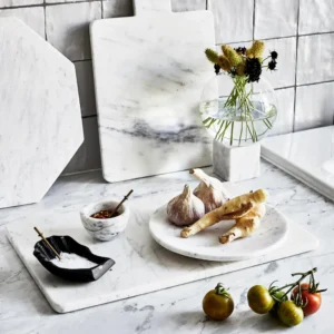 White marble serving board with garlic, ginger, and small bowls of spices.