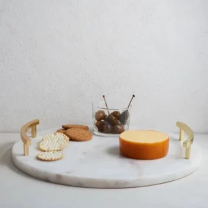 Round marble serving tray with gold handles, holding cheese, crackers, and olives.