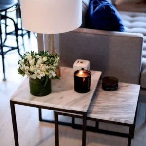 Marble nesting tables with flowers, candle, and lamp.